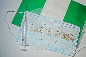 Nigerian flag under words Lassa fever outbreak concept. protective breathing mask and syringe. Lassa hemorrhagic fever LHF endemic