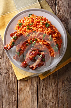 Nigerian food party: Jollof rice with fried chicken wings close-up. Vertical top view