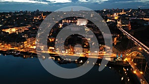 Night aerial view of Dom Luis I Bridge over Douro river against backdrop of lighted Porto city, Portugal