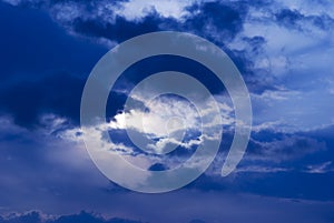 Night blue sky and moonlight background. The magic moon shines in the night sky through dark blue clouds