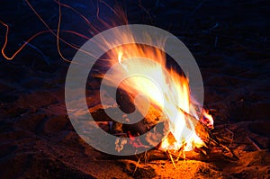 Night bonfire on the sand rolling in sparks