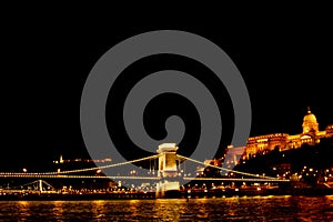 Night Budapest, glowing in gold. The chain bridge over the Danube is illuminated by light bulbs. photo from the river