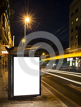 Night bus station with blank billboard