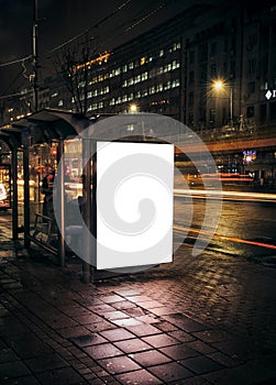 Night bus station with blank billboard