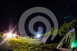 Night camping under starry sky. Glowing tourist tent, under beautiful evening sky full of stars and Milky way, city