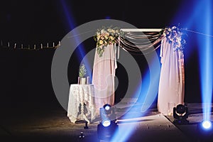 Night ceremony with light and fire show. The wedding arch is decorated with flowers at night ceremony outside in the
