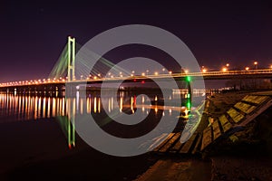 Night city. Beautiful glowing bridge over the river