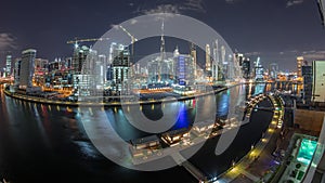 Night city Dubai near canal with bright skyscrapers aerial timelapse