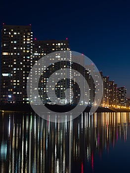 Night city. Houses are reflected in the water