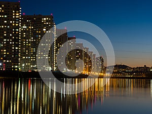 Night city. Houses are reflected in the water