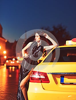 Night city with princess in celebrity style. Luxury woman in evening dress at night city go to prom on taxi. Girl with