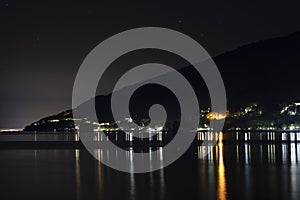 Night city in the reflection of the water of the sea. Night beach of pebbles Abkhazia Gagra. Black night, highlands, tourism,