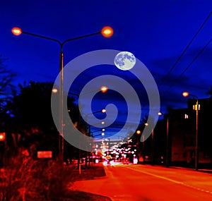 Night city sleeps ,lanterns on the road, cars lights blurry , blue sky and full moon with moonlight panorama