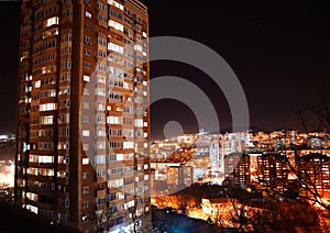 Night city with tall buildings and floating lights of cars