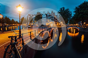 Night city view of Amsterdam. Illuminated bridge on Herengracht canal. Typical dutch houses in hour lights, Holland