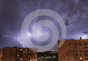 Night city view under thunderstorm with strike of lightning.