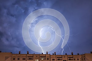 Night city view under thunderstorm with strike of lightning.