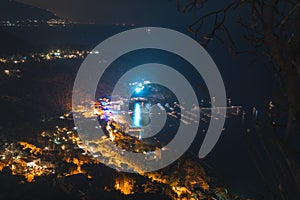 Night city. View of the village from the top of the mountain, streets and lights, a bay with boats. Travel and vacation concept in