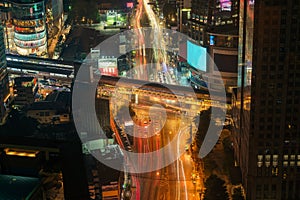 Night cityscape of intersection street with light trails from the moving busy transport on highway road in modern Bangkok city