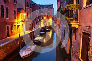 Night cityscape of Venice, Italy. Boats and houses on water canal illuminated lights of city lanterns