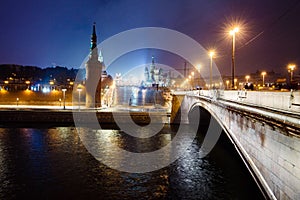 Night cityscape view of Moscow Kremlin, Vasilievsky Spusk and Red Square, embankment, street lights at winter snowfall, Russia. photo