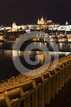 Night colorful snowy Christmas Prague Lesser Town with gothic Castle with Charles Bridge, Czech republic