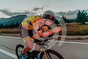 Night drive. Full length portrait of an active triathlete in sportswear and with a protective helmet riding a bicycle in
