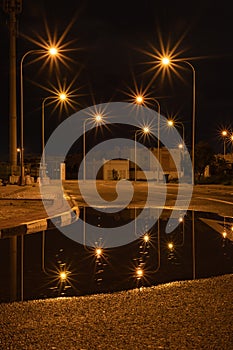 Night empty road with reflection of street light on water