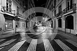 Night on the empty streets of the old city of Lisbon. Empty tram tracks. Portugal. Black and white