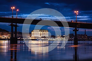 Night european city in colorful lights and reflection in water, Kiev, Ukraine. Pedestrian bridge across the Dnieper river