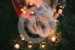 Night fine art outdoor wedding details: summer or spring ceremony with decor lowlight candles standing on chair covered