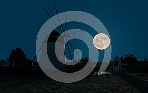 A Spanish windmill with the full moon in the sky in the background. photo