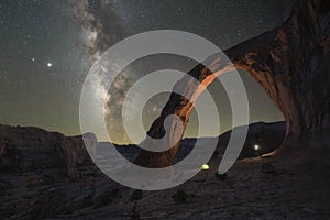 Night hiker standing under Corona Arch with the Milky Way Galaxy