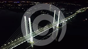 Night illuminated industrial bridge traffic transportation crossing river sea aerial city panorama