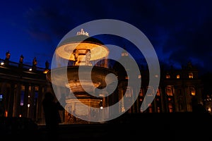 night image of a tourist photographing one of the illuminated fountains in St. Peter\'s Square