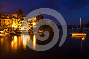 Night on lake Como harbor, illuminated buildings a