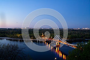 Night landscape. The city of Kiev, Ukraine, Europe. Pedestrian bridge across the Dnieper River. Beautiful lighting and