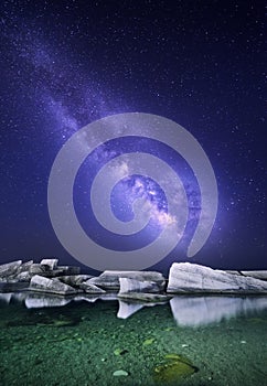 Night landscape with colorful Milky Way at the sea with stones. Starry sky. Space background.