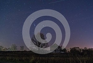 night landscape of historic old architecture with stars in the sky and flying starlink satellite