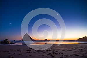 Night landscape on the pacific ocean, Cannon beach. Stars and cliffs, sunset time