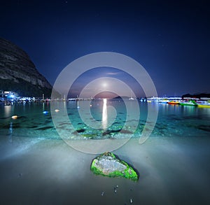 Night landscape at the sea with stone, yellow sand and lunar path. Moonrise. Travel background.