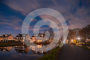 Night landscape with starry sky in the Dutch village of Streefkerk. Houses with bright light reflecting in the shine of the water