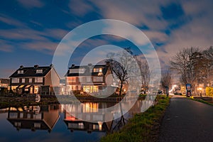 Night landscape with starry sky in the Dutch village of Streefkerk. Houses with bright light reflecting in the shine of the water
