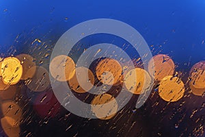 Night lights of urban traffic, wet window in rainy weather. Abstract background for banner design. Night city life, cars