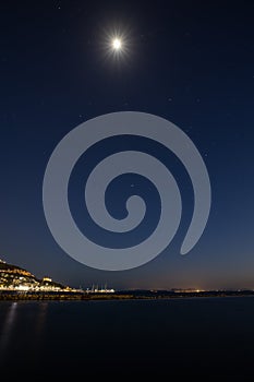 Night long exposure of the sky with the bright moon and stars over the sea