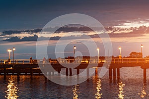 night molo pier with lantern yellow light at Polish village Jastarnia, sunset