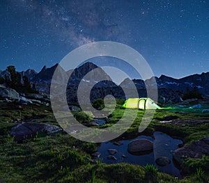 Night mountain landscape with illuminated tent.