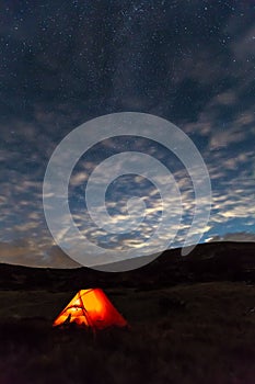 Night mountain landscape with illuminated tent