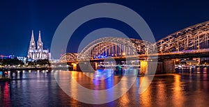 Night panorama of the illuminated Hohenzollern bridge over Rhine river. Beautiful cityscape of Cologne, Germany