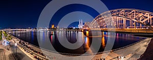 Night panorama of the illuminated Hohenzollern bridge over Rhine river. Beautiful cityscape of Cologne, Germany with cathedral
